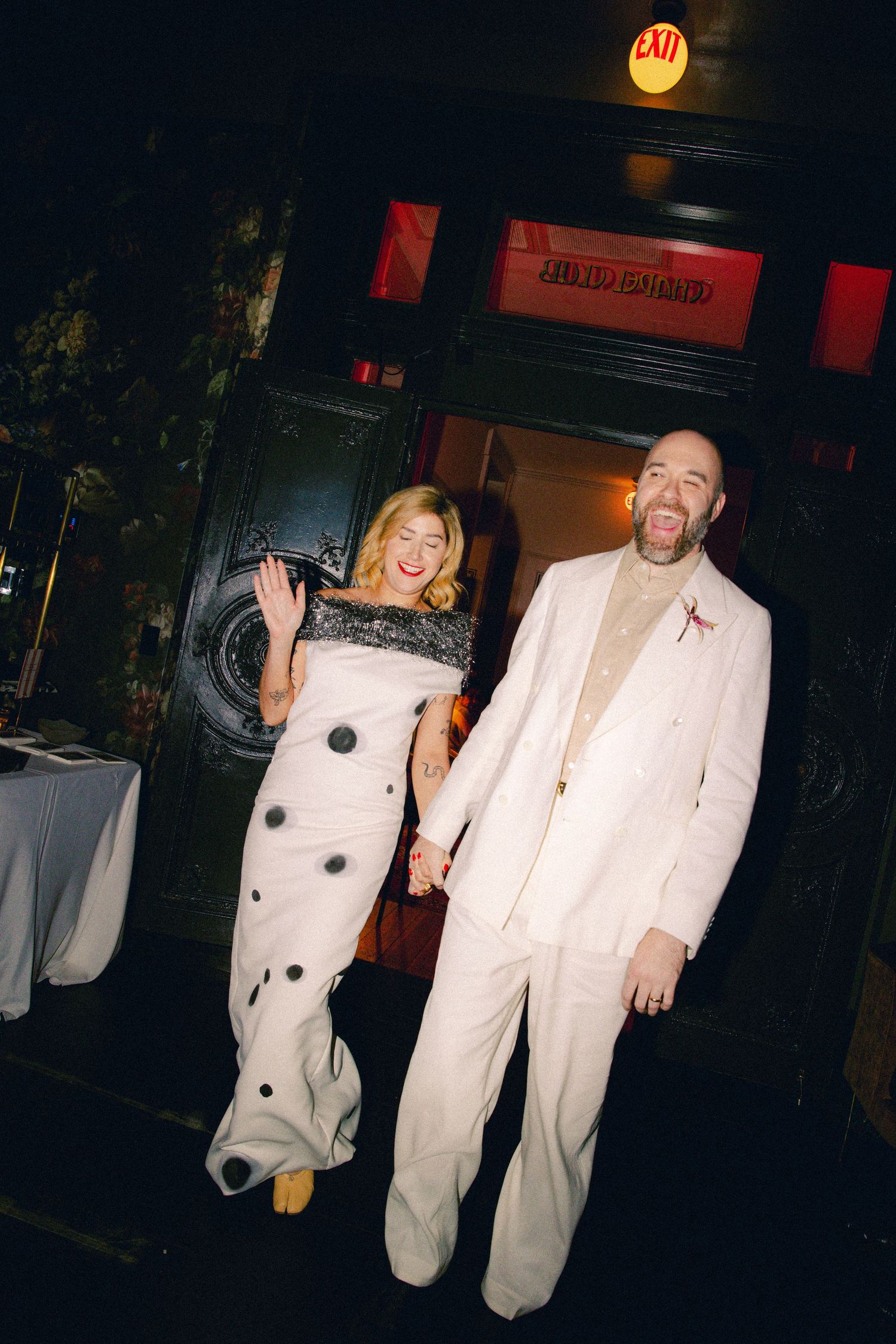 Joyful newlyweds in white wedding attire laugh while making grand entrance at New Orleans reception.