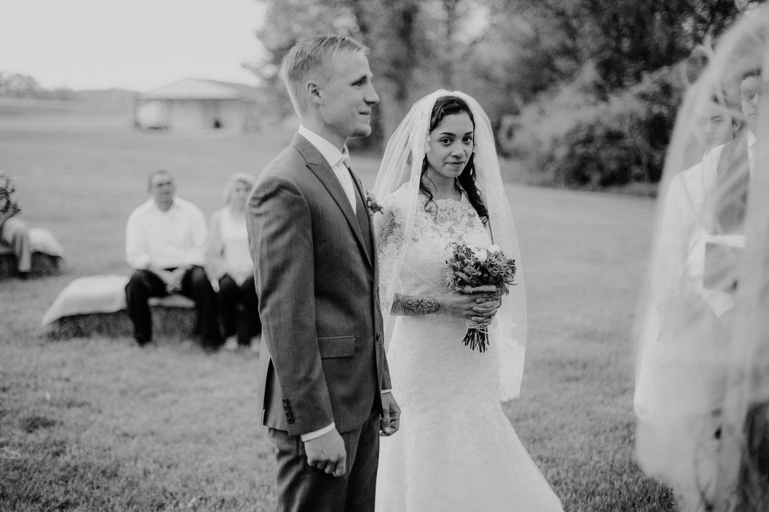 Bride and groom standing together during outdoor wedding ceremony on green lawn.