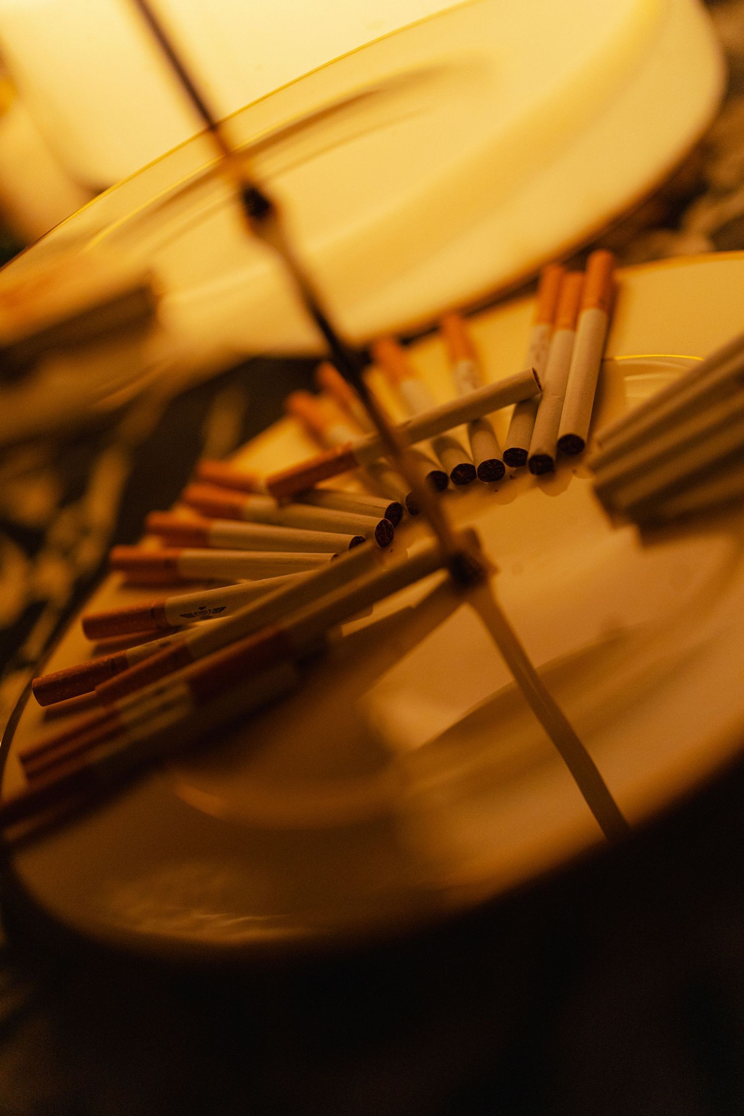 Artistic blurred close-up of cigarettes arranged on a spinning golden decorative plate.