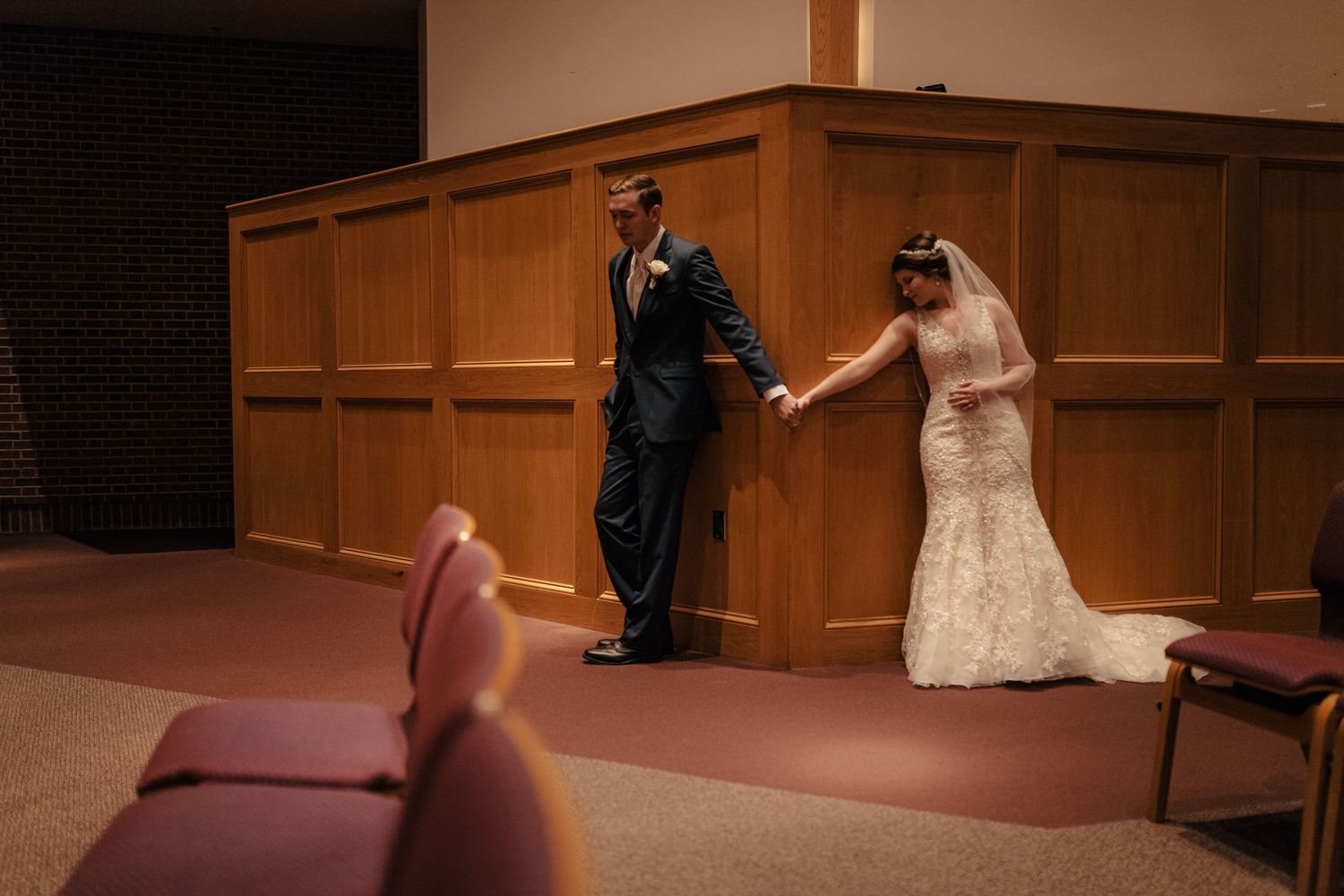 Bride and groom share a tender first look moment holding hands in a church before the ceremony.