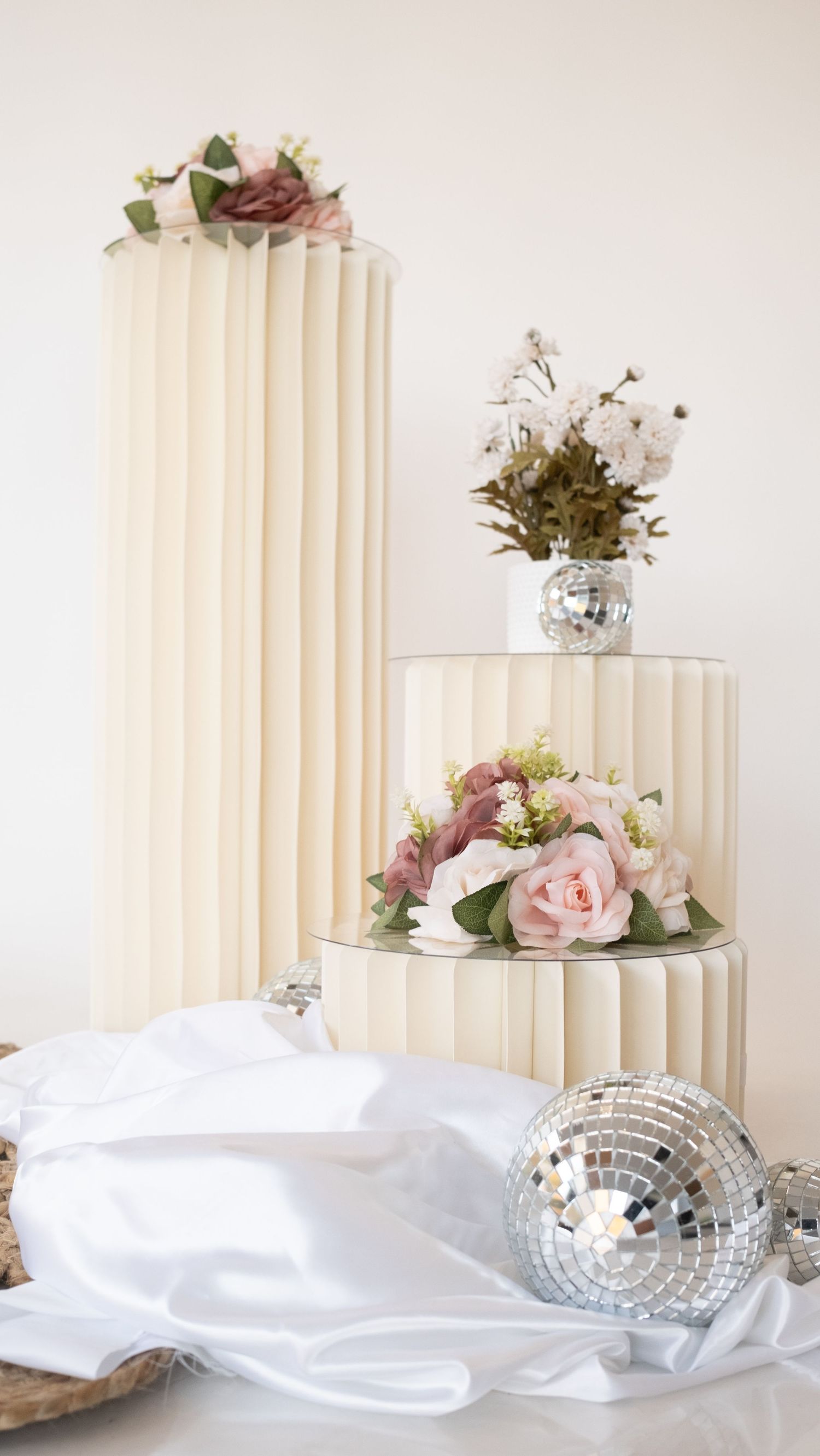 Three-tiered white pleated display stands decorated with pink roses and disco ball accents. Perth WA Photo booth Hire Event Booth