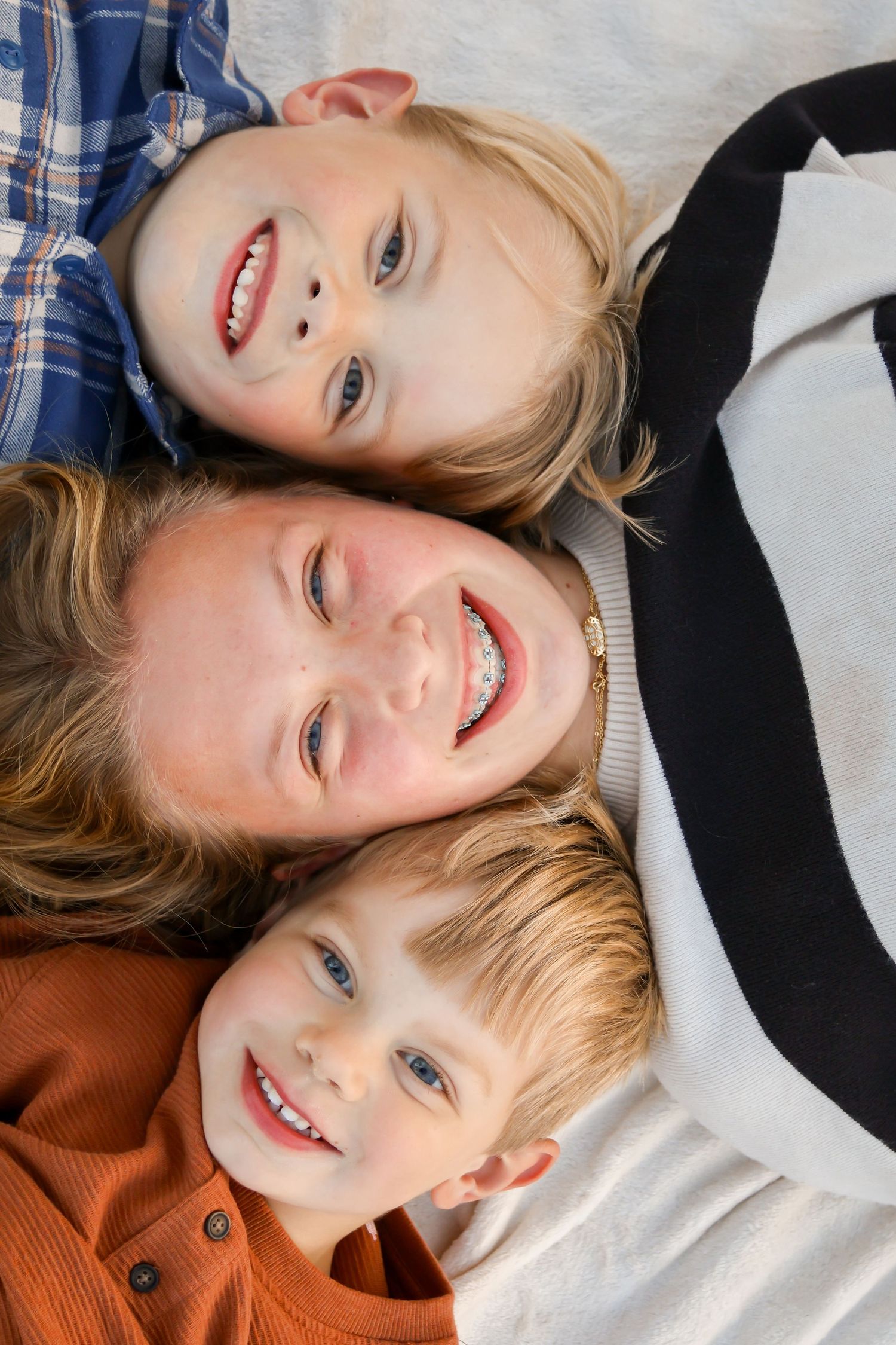 Close-up photo of three children's faces smiling