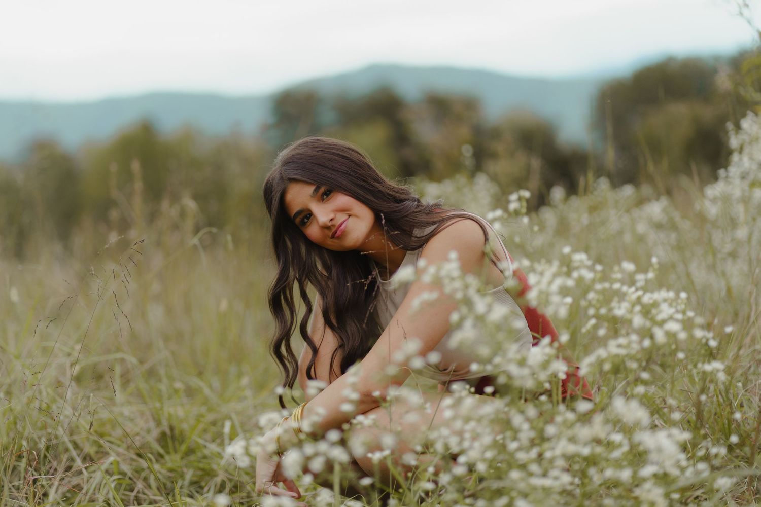 A dreamy portrait session in a wildflower meadow with white daisies and tall grass at golden hour.