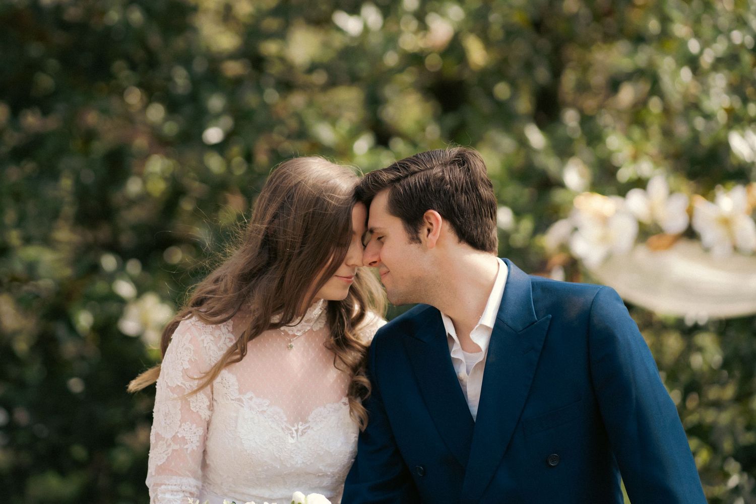 A romantic couple shares an intimate moment outdoors in formal attire.
