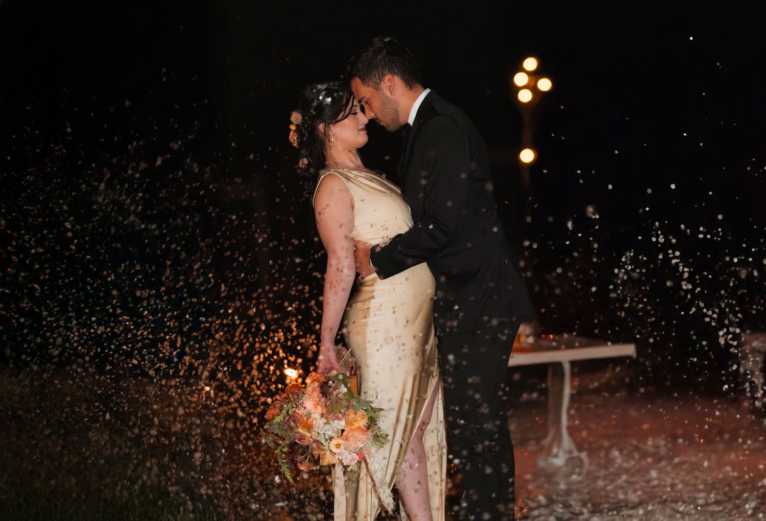 A romantic wedding couple shares an intimate moment under glowing lights as sparkles fall around them.