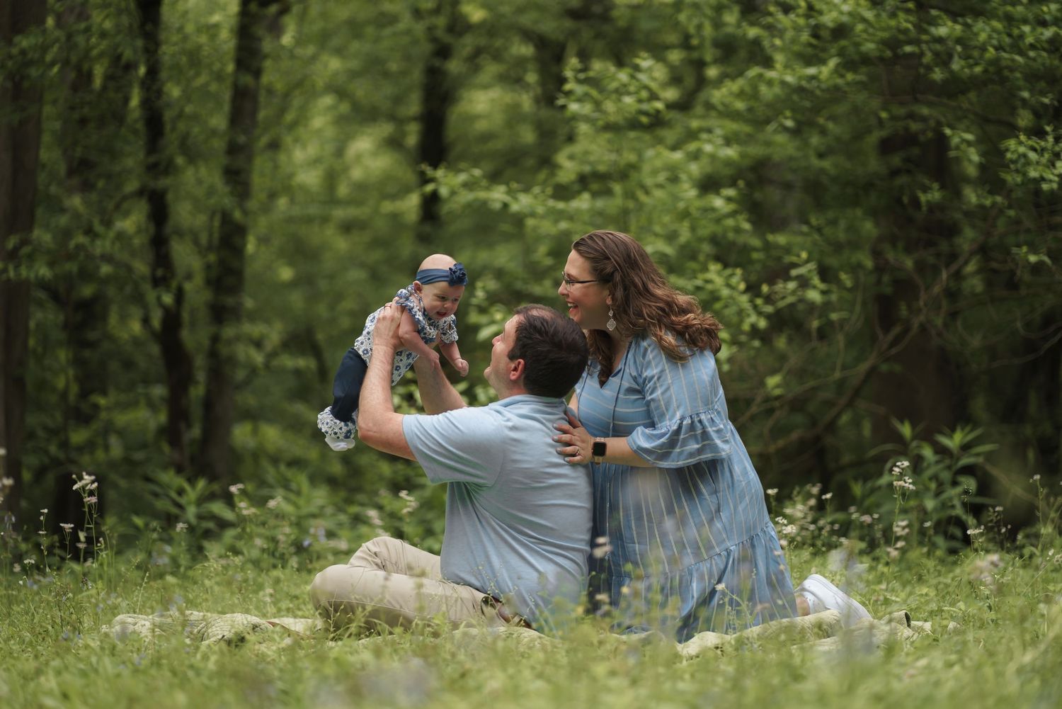 Family sharing a joyful moment together in a lush green forest setting.
