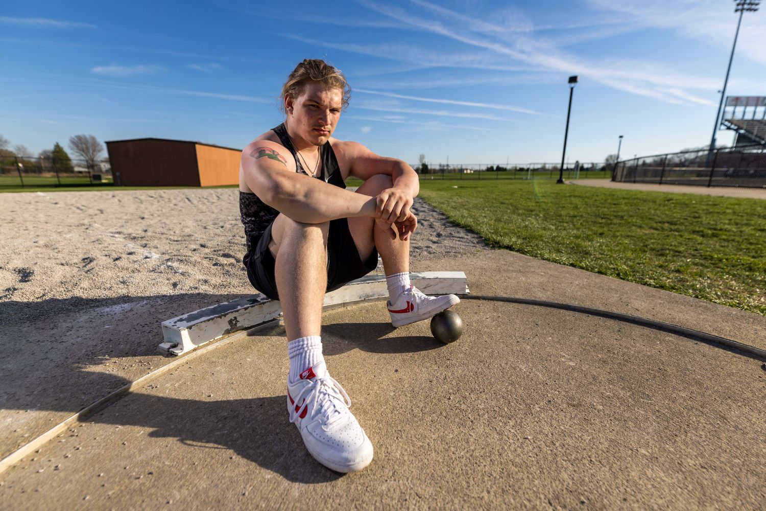 I high school senior boy sitting with his shot-put.