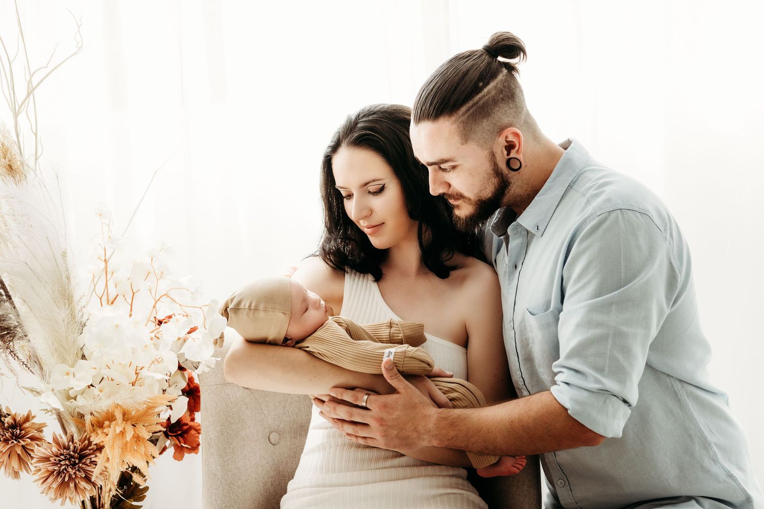 Intimate indoors lifestyle photo with new baby and floral arrangements.