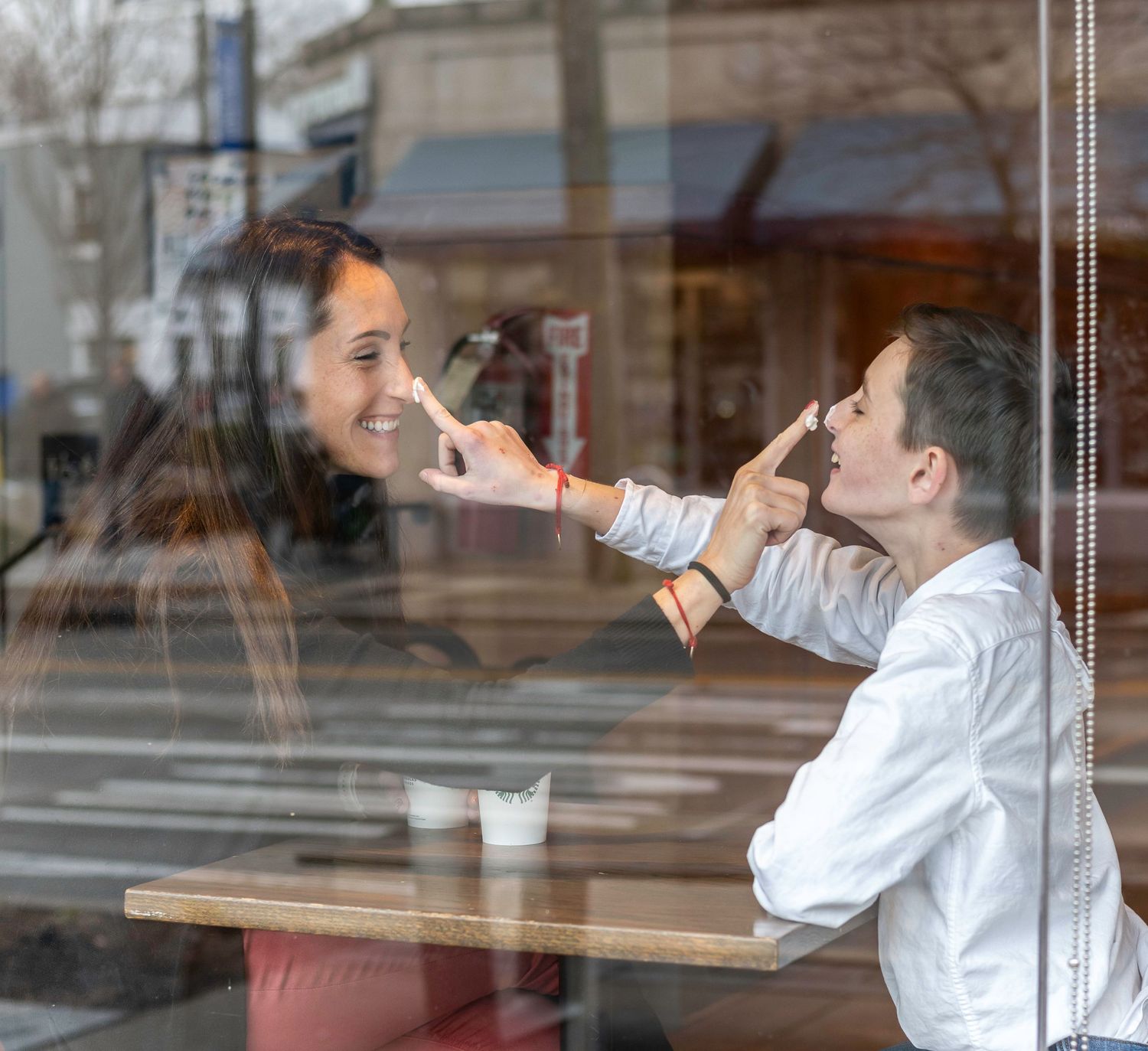 Mother and son portrait in Starbucks putting whip cream on each other's nose. It is a cute representation of the mother son relationship