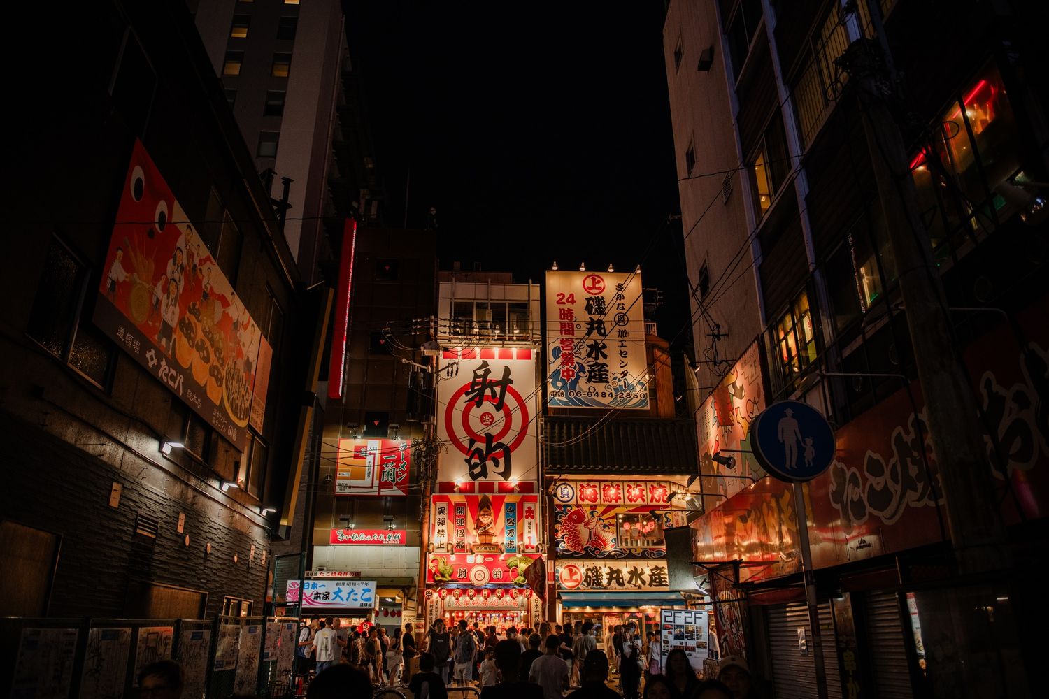 Vibrant neon signs illuminate a busy street in Tokyo's entertainment district at night.