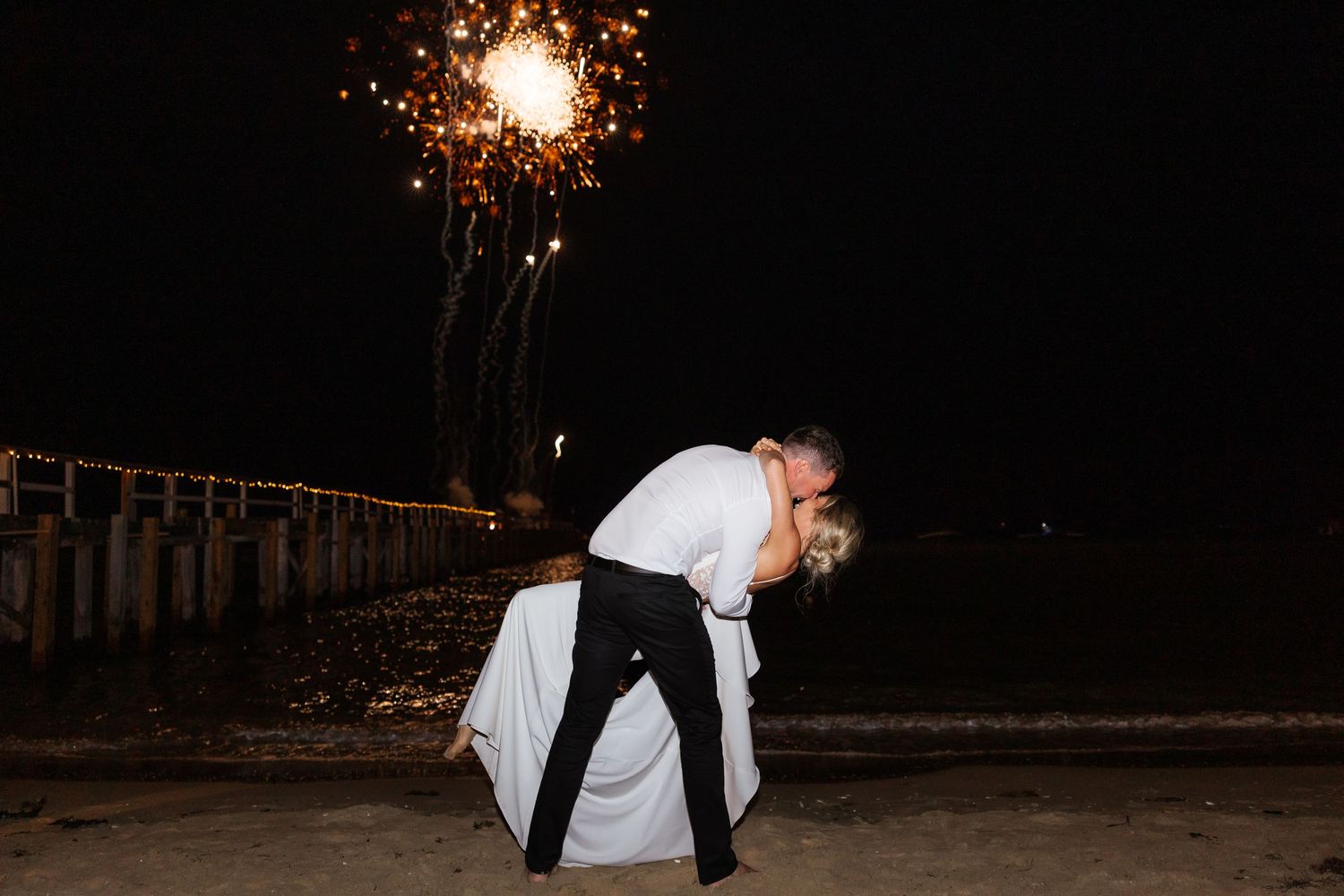Wedding couple silhouetted against sparklers in nighttime celebration photos.