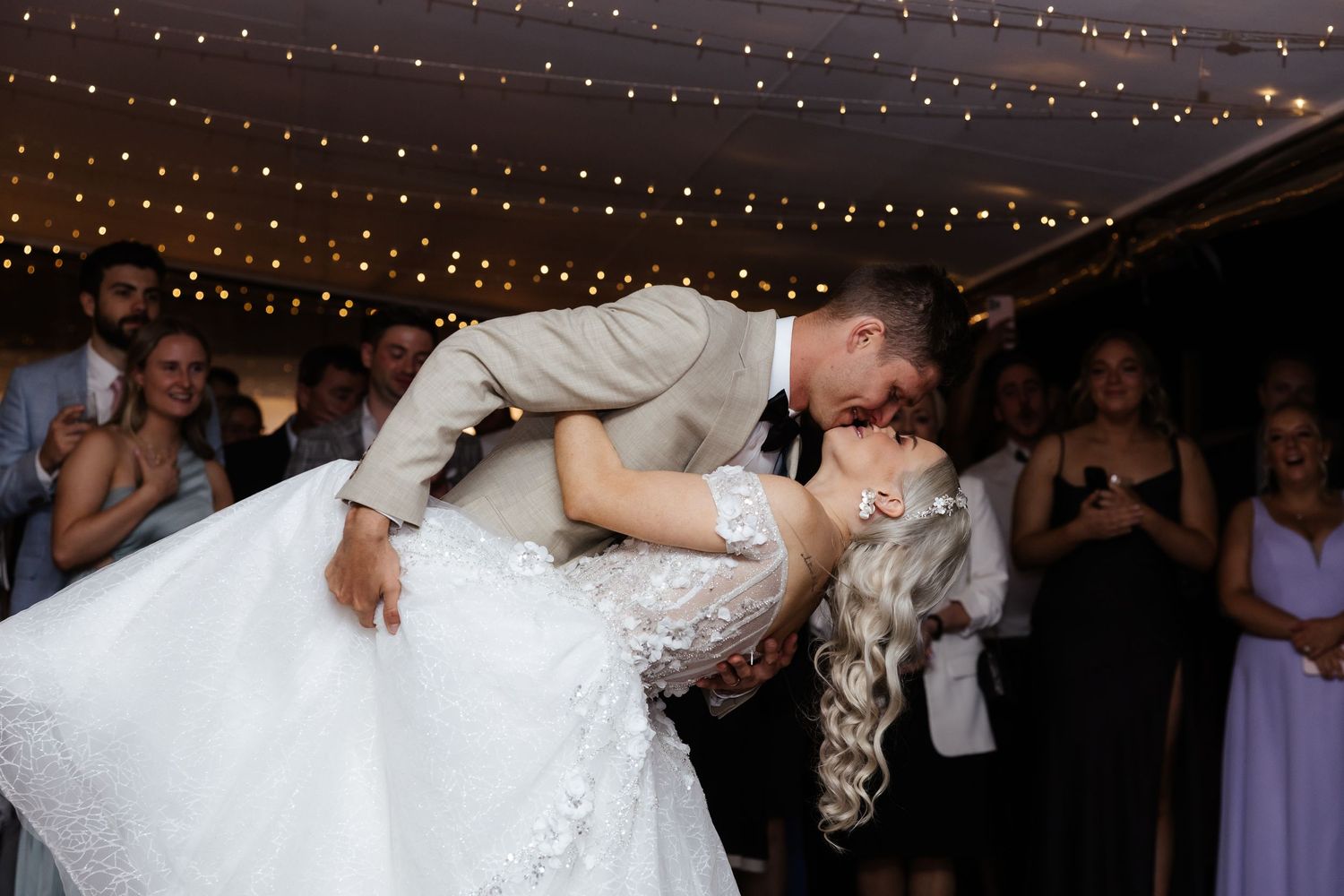 First dance under twinkling lights at wedding reception.