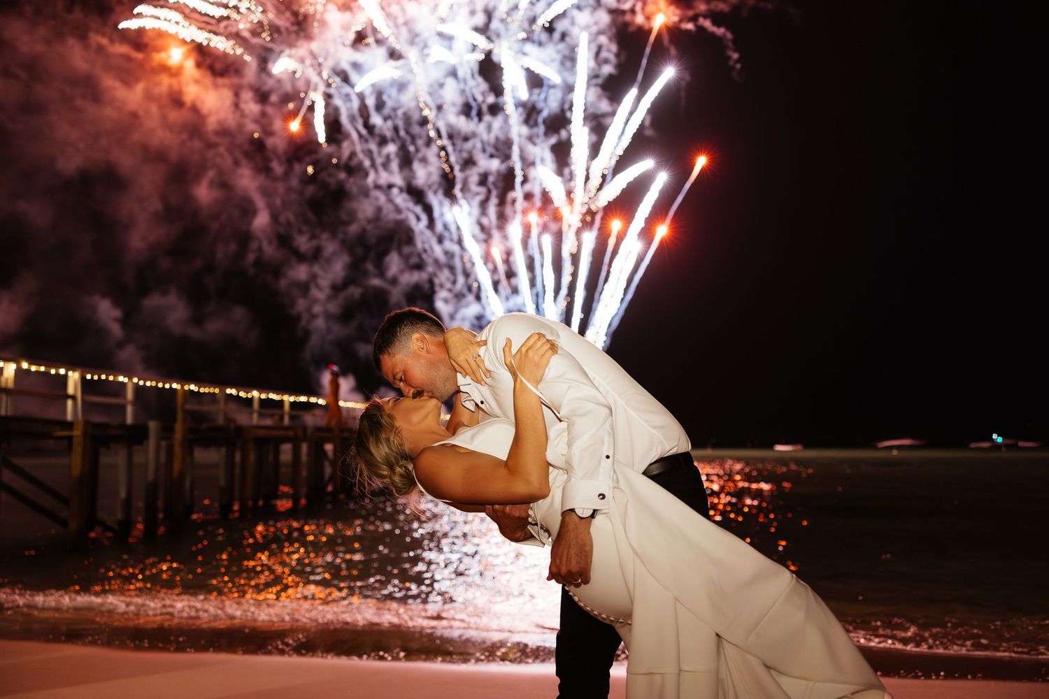 Dramatic nighttime wedding photos with fireworks display in the background.