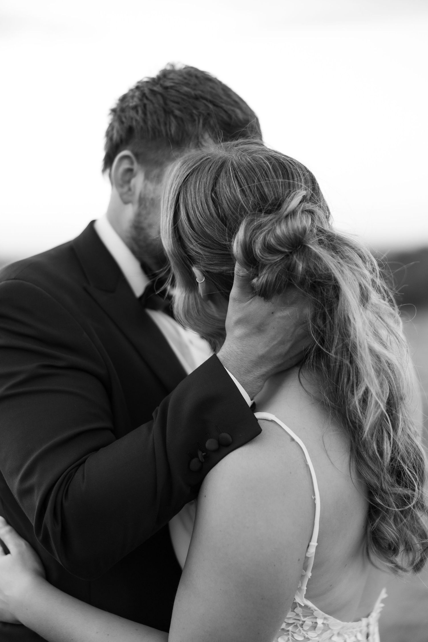 Four romantic black and white photos show a tender kiss sequence between a couple at their wedding celebration.