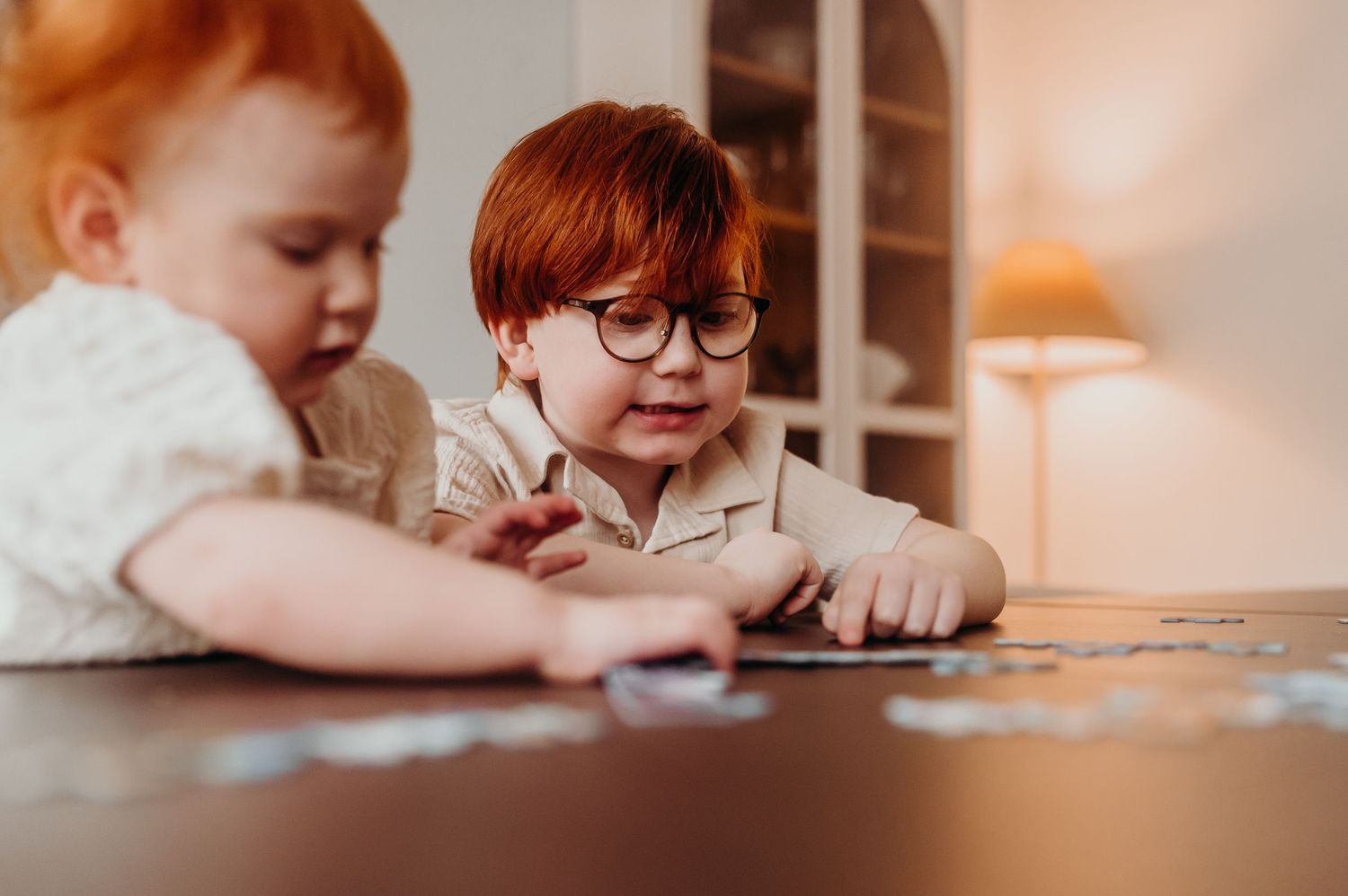 Två barn som spelar spel vid köksbordet under en avslappnad familjefotografering i hemmet.