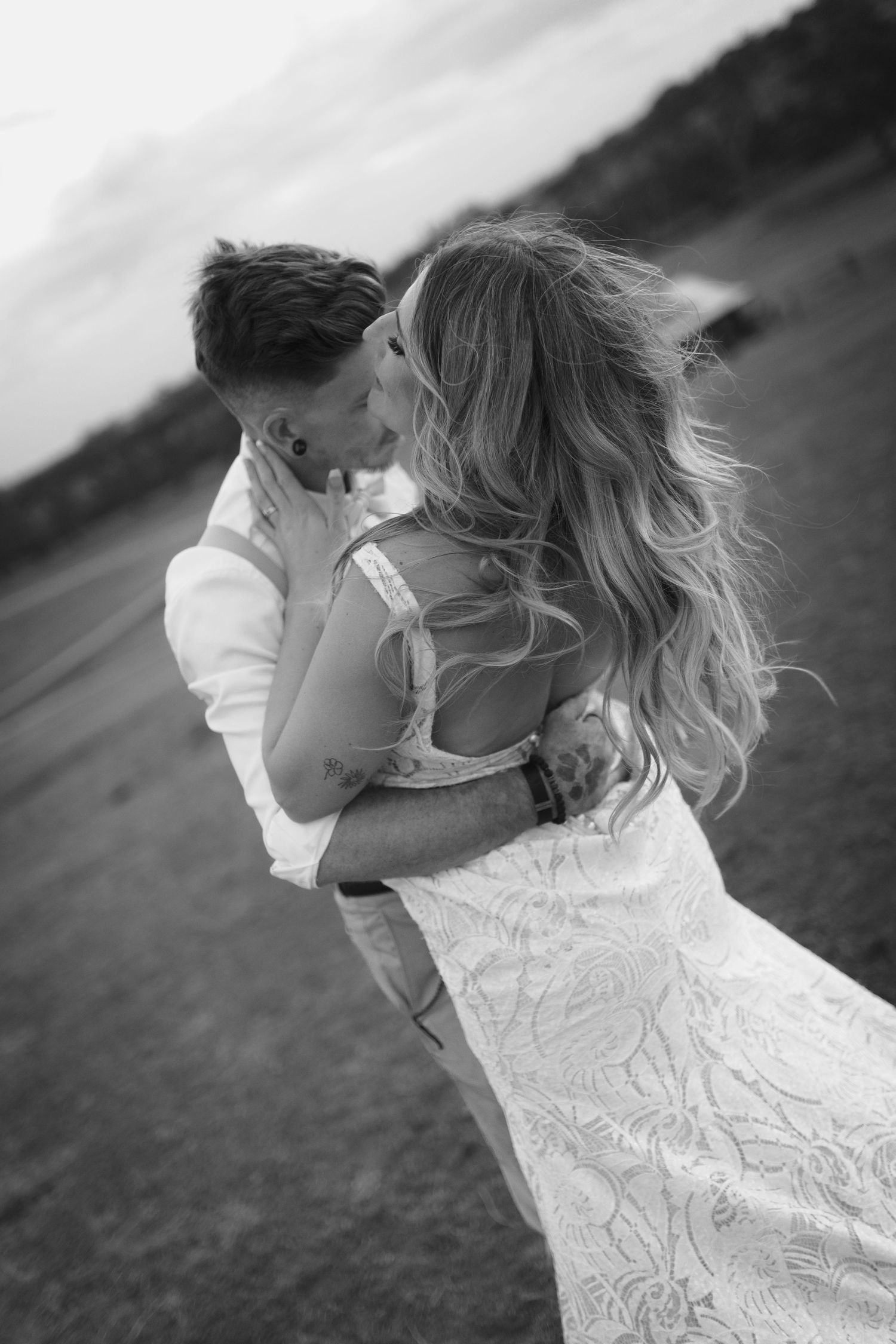 A romantic black and white embrace between newlyweds in an outdoor setting.