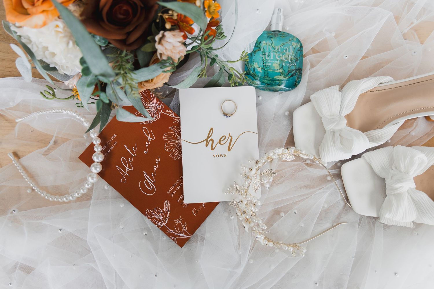 Wedding details including rustic leather vow books, turquoise decor, and floral arrangements on white fabric.