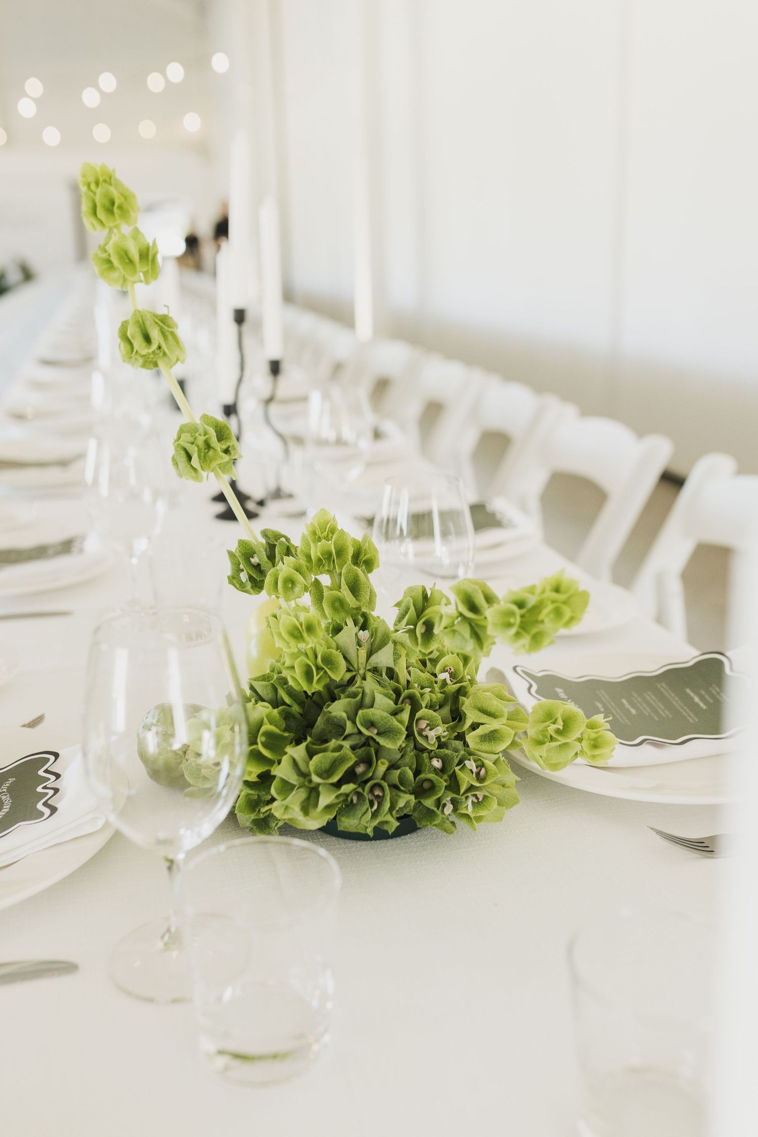 Modern wedding table setting with bright green floral centerpieces and white place settings.