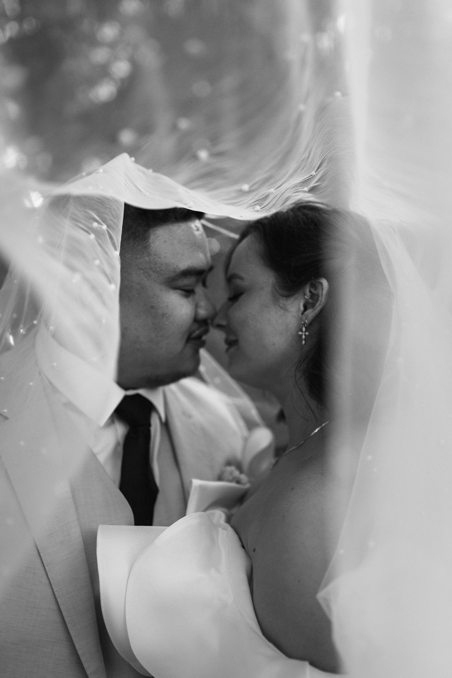 Intimate black and white wedding photo through delicate veil fabric.
