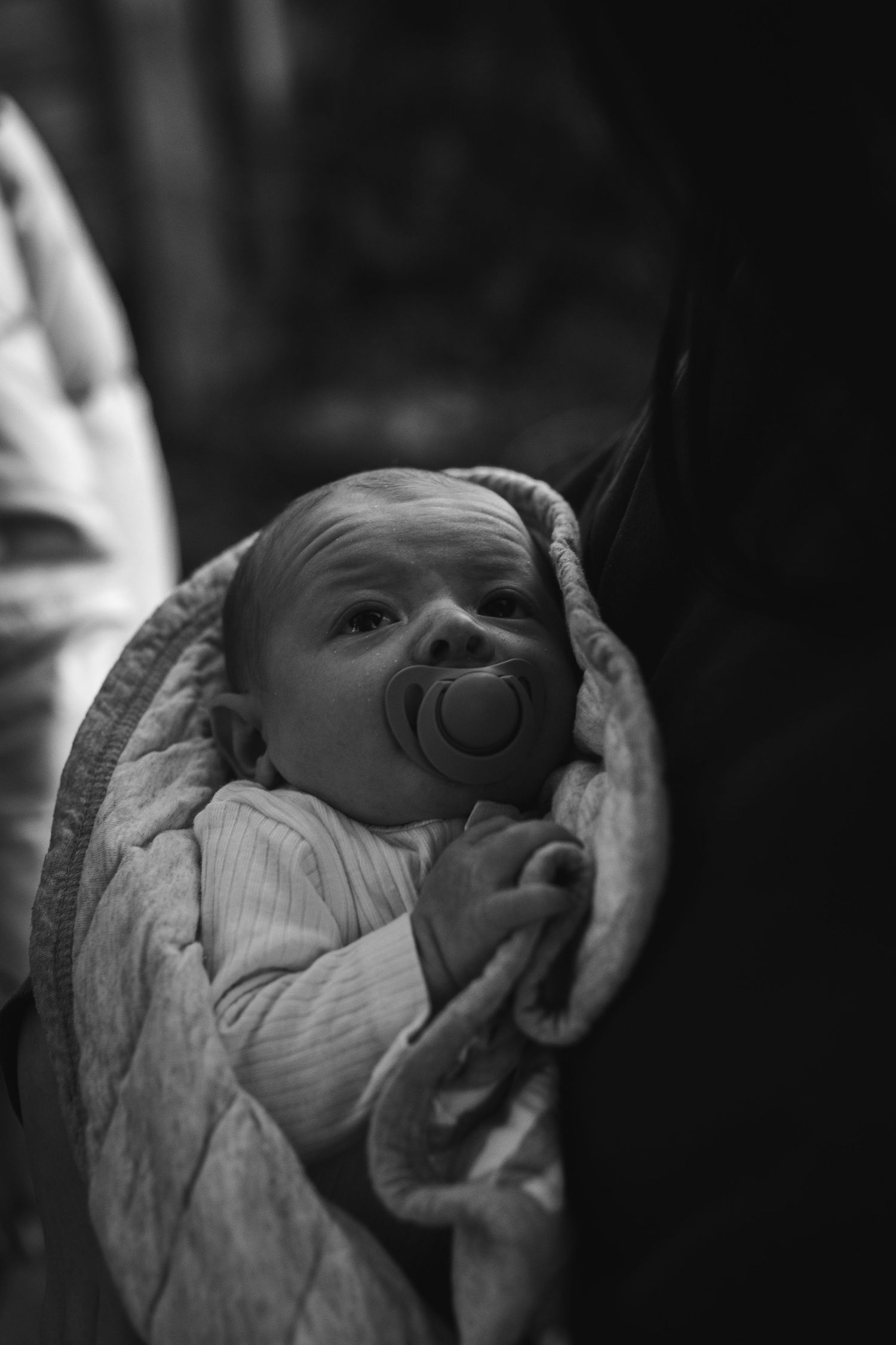 Black and white portrait of a baby wrapped in blanket with pacifier.
