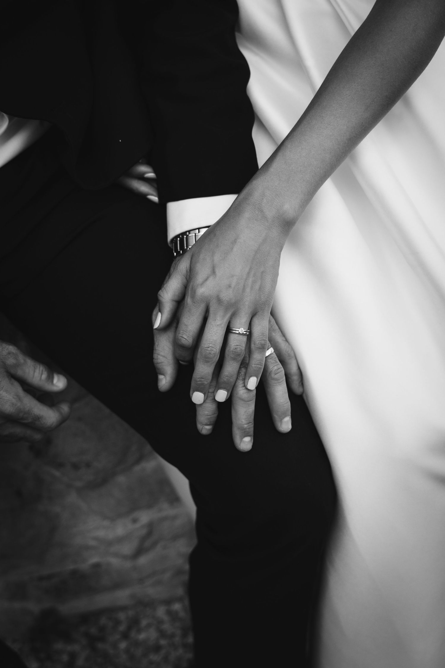 Close-up black and white photo of hands with wedding rings.