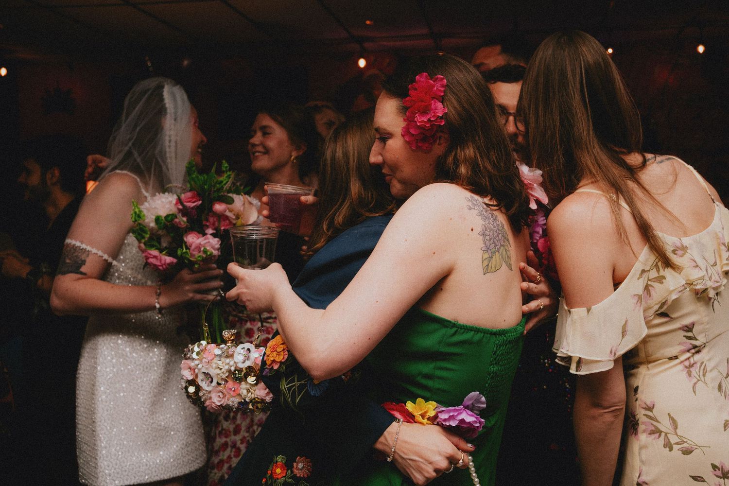 Guests dancing and celebrating at a colorful wedding reception, with flowers and festive attire.