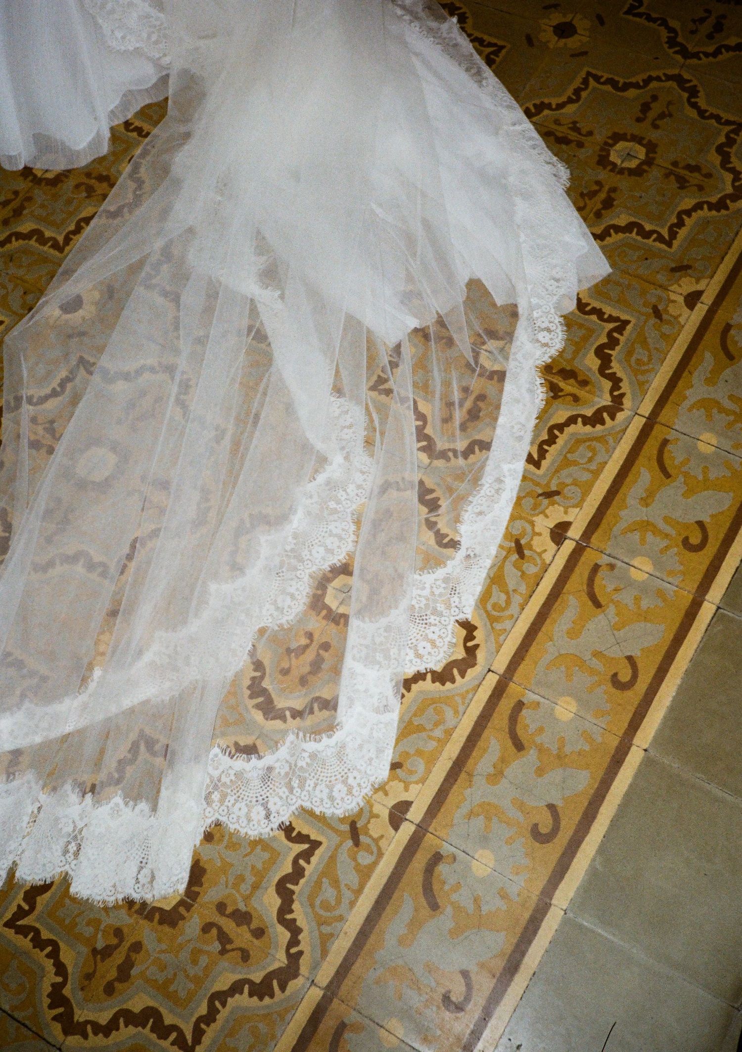 White lace bridal veil trailing on ornate golden mosaic tile floor in elegant wedding venue.