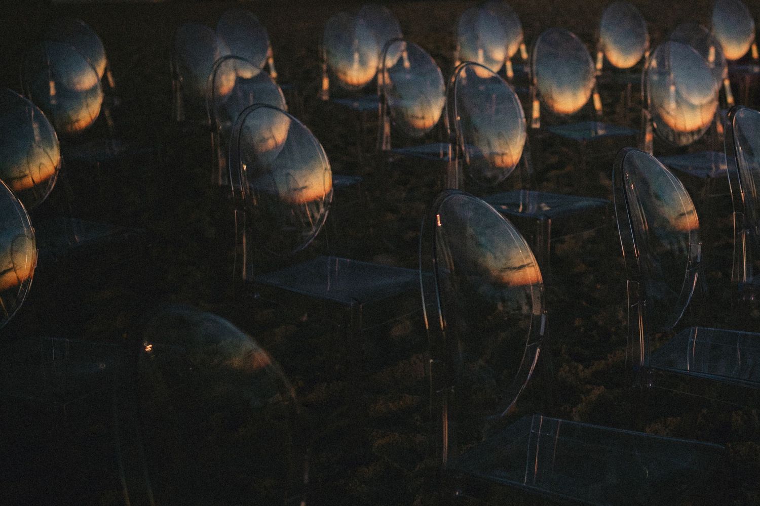 Rows of reflective metallic spheres capturing sunset light in a dark outdoor installation art display.