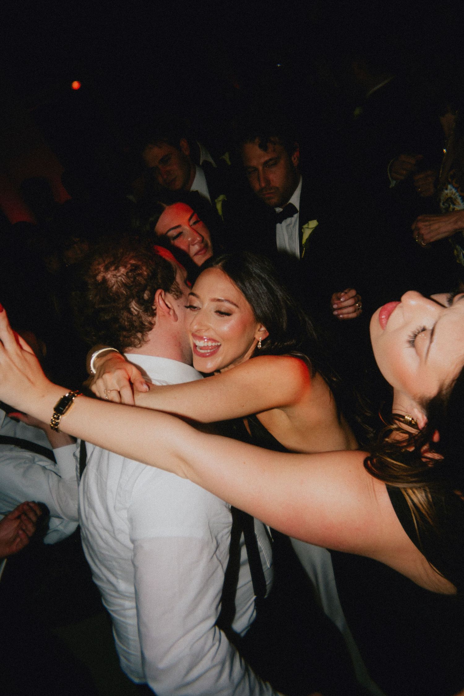 Guests dancing and embracing joyfully at a formal wedding reception party on the dance floor.