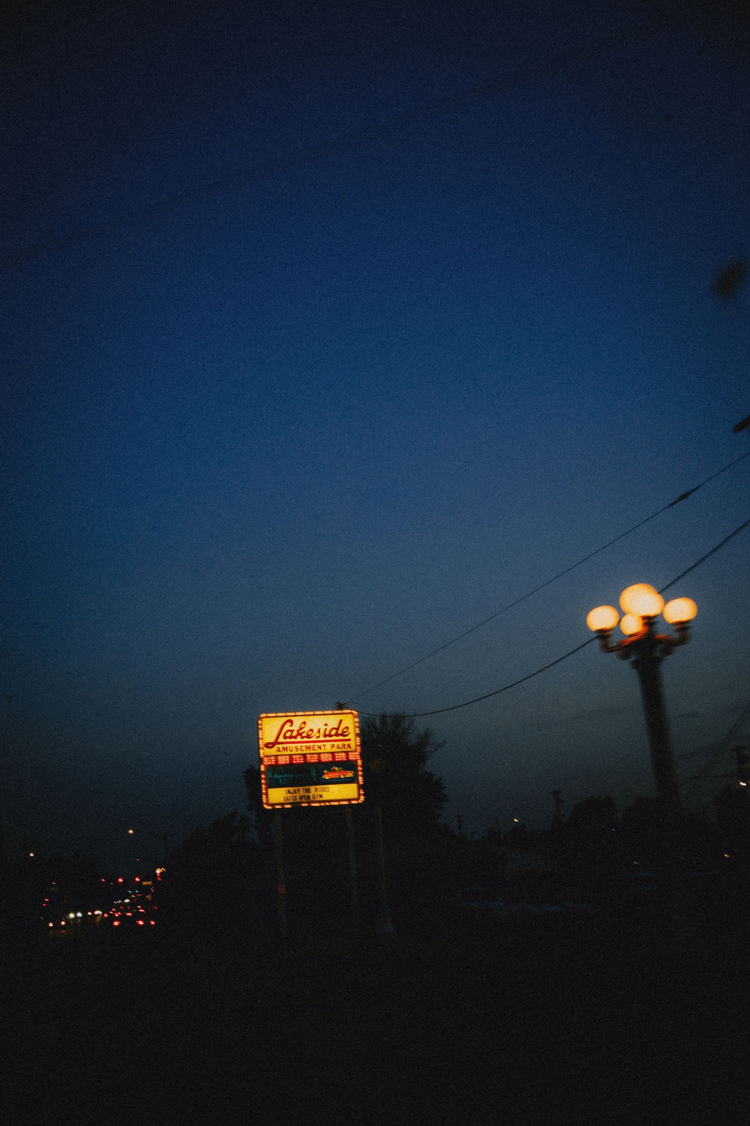 Lakeside sign glowing at dusk with street lamp lights against a deep blue twilight sky.