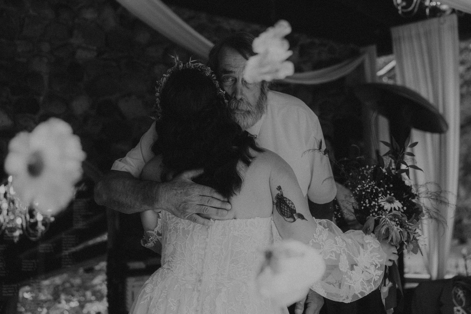 Black and white wedding photo of a couple sharing an emotional embrace during their outdoor ceremony.
