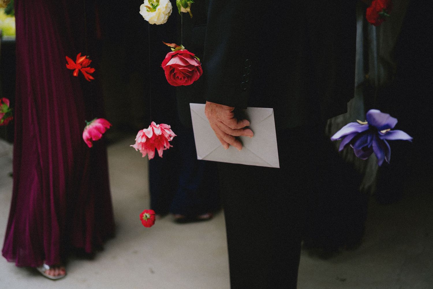 Person in black suit holding a card surrounded by floating colorful roses and flowers at a formal event.