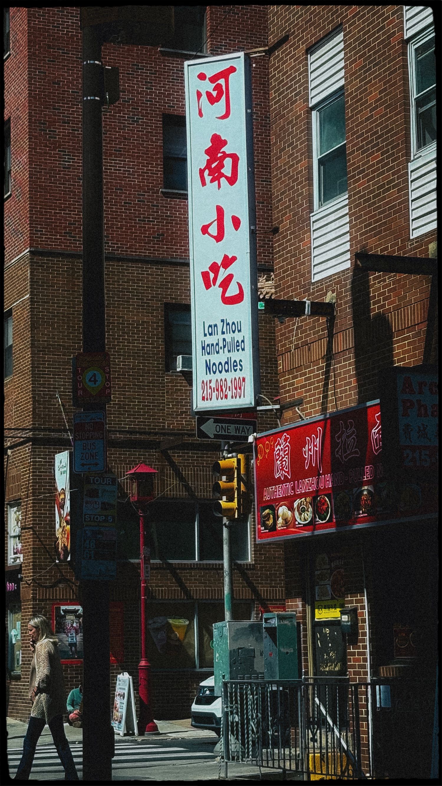 Chinatown street scene featuring Lan Zhou Hand-Pulled Noodles sign with Chinese characters on a brick building in Philadelphia.