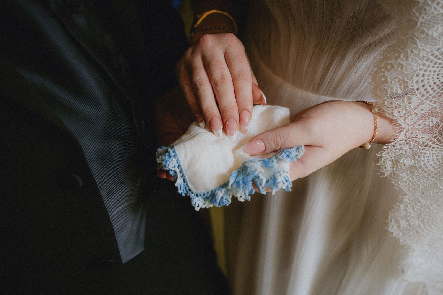 Bride and groom holding a delicate blue lace wedding garter during their ceremony.