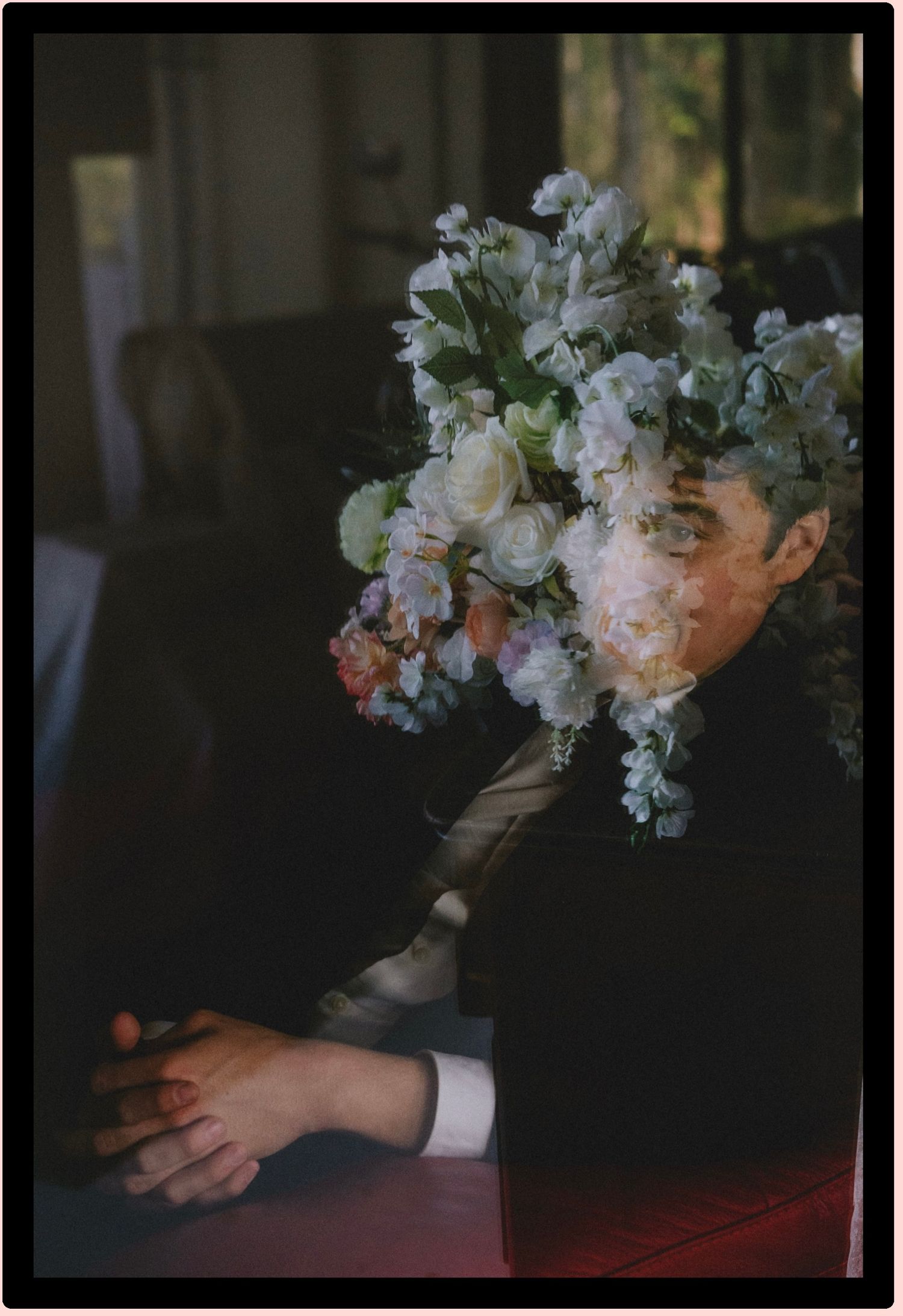 Double exposure portrait of a man in a dark suit with white and blue flowers overlaid on his face.