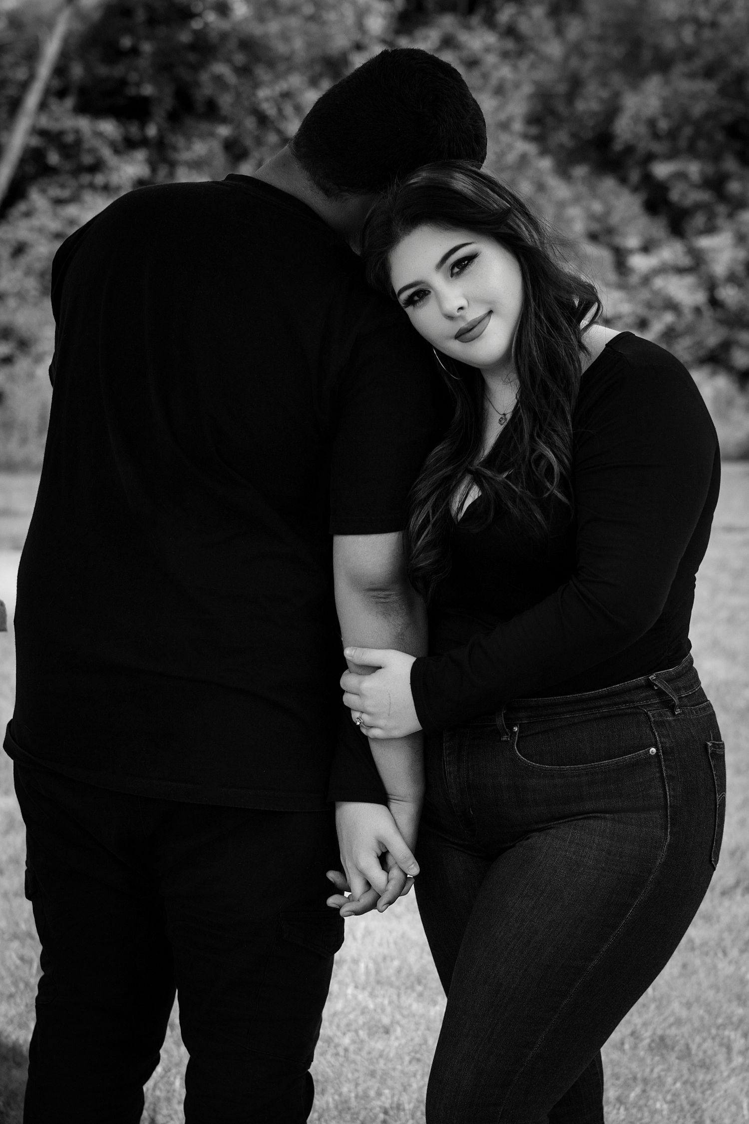 Black and white romantic couple portrait with woman smiling at camera while leaning on partners shoulder.