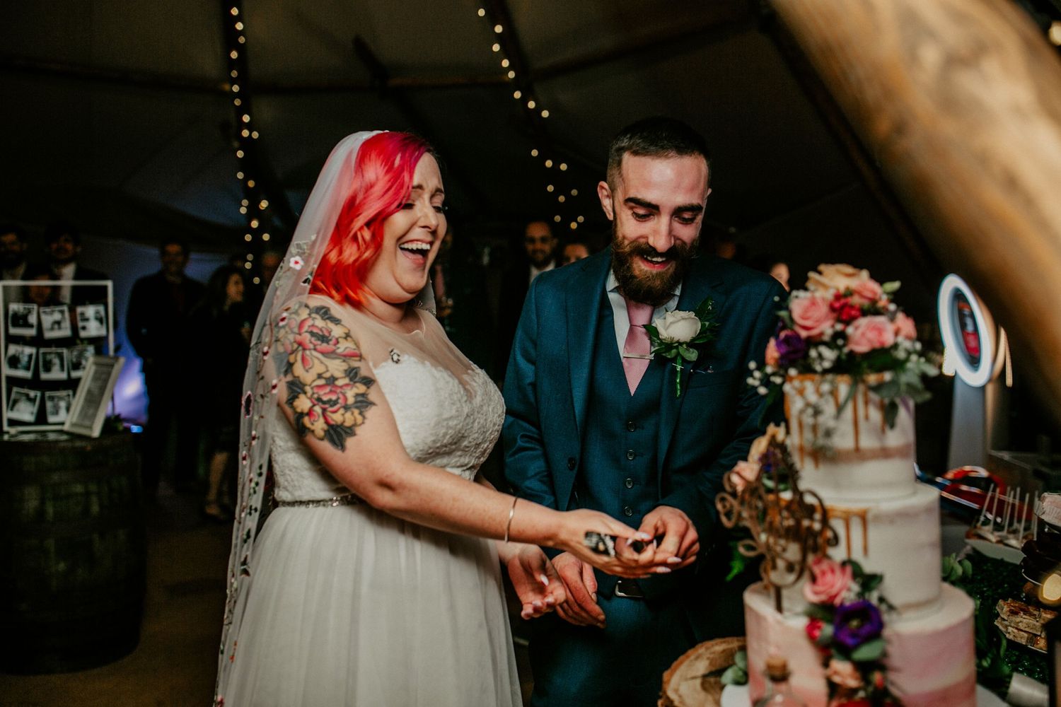 A picture-perfect cake – The newlyweds pose beside their wedding cake, a beautifully decorated centrepiece at the reception.