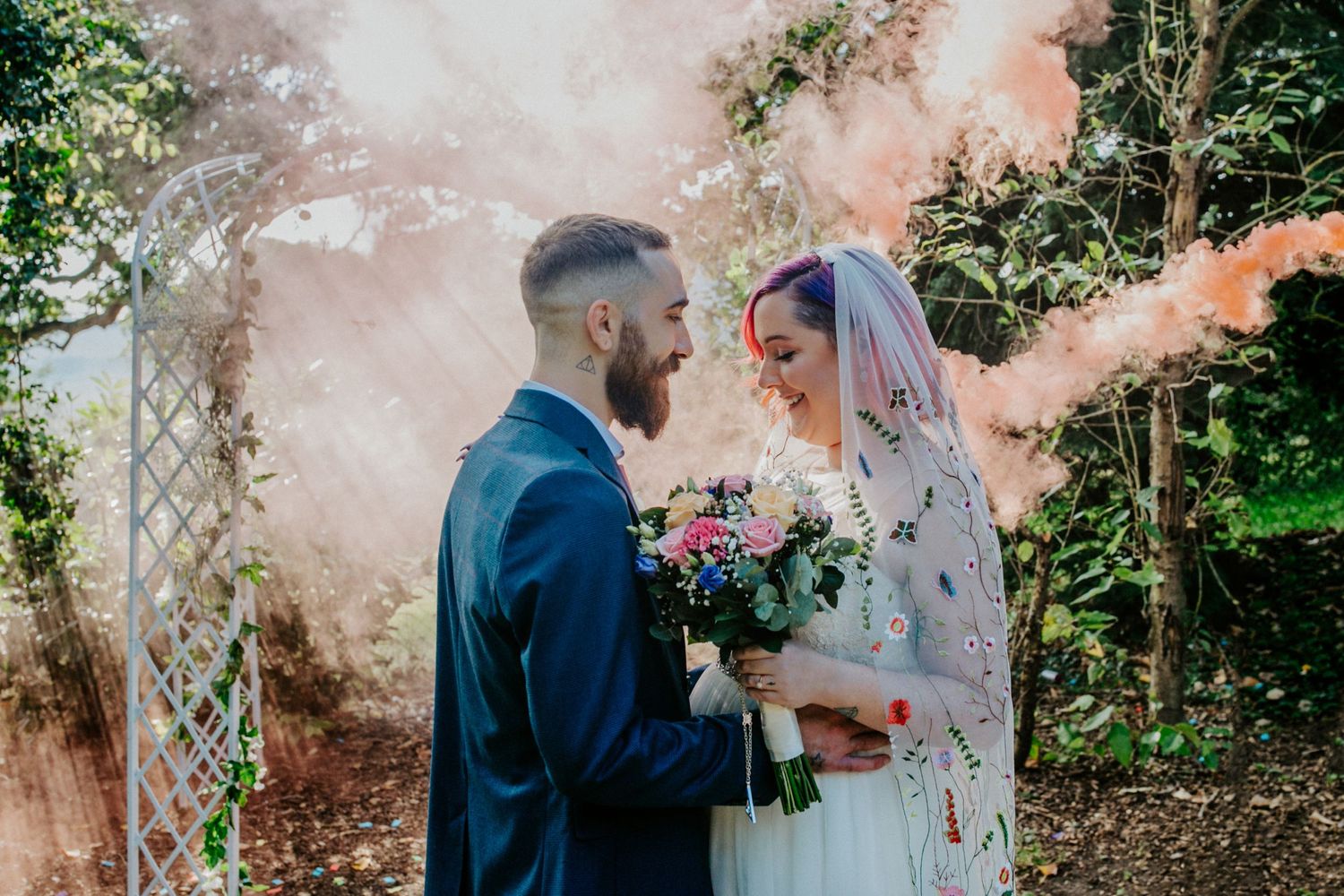 The newlyweds take a moment as colourful smoke bomb surrounds them in the Lodge Farm House garden