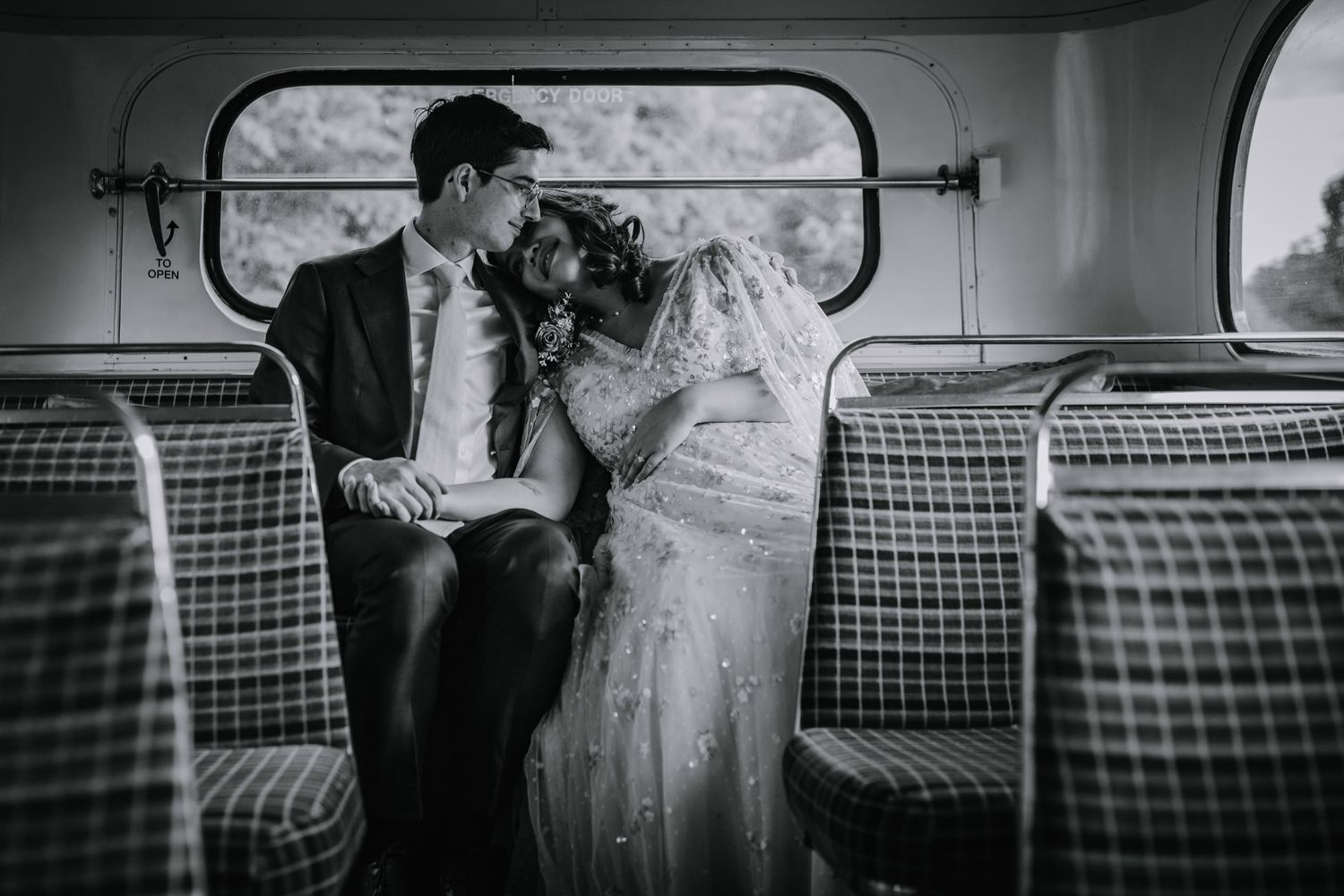 Bride rests her head on the groom's shoulder during a natural portrait session on London wedding bus.