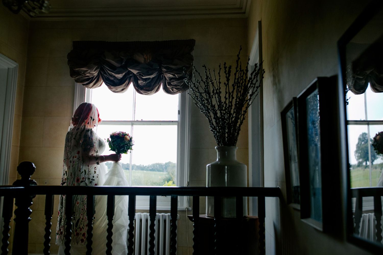 A bride’s view – The bride admires her guests arriving from the window, she holds her round bouquet
