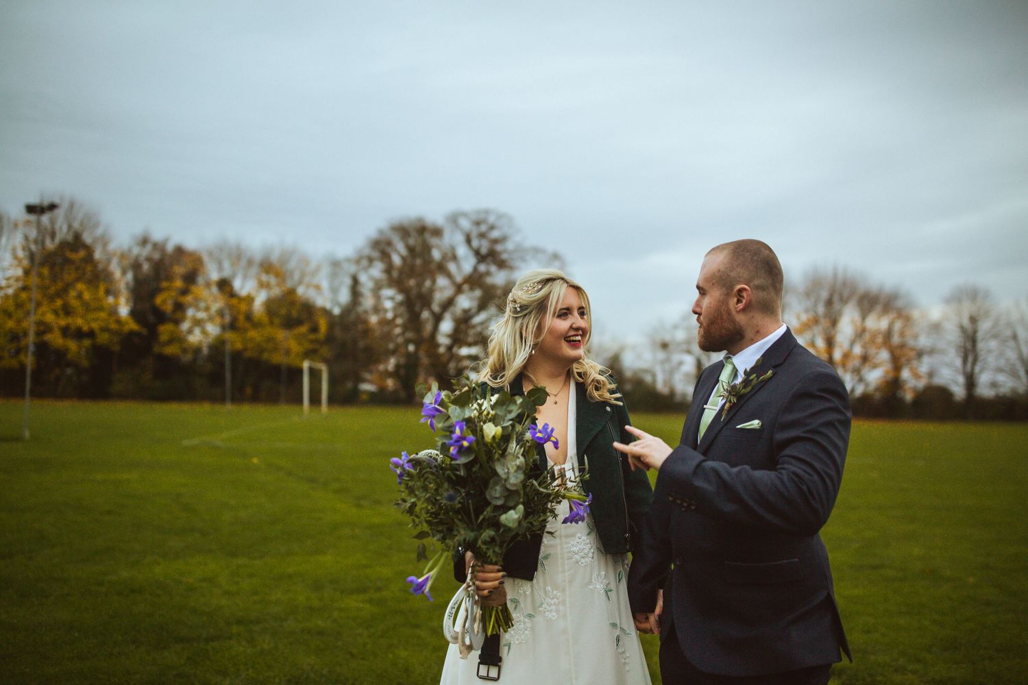 Bride and Groom outside Cottered Village Hall on a field  Hertfordshire, Photographer RELM Photography