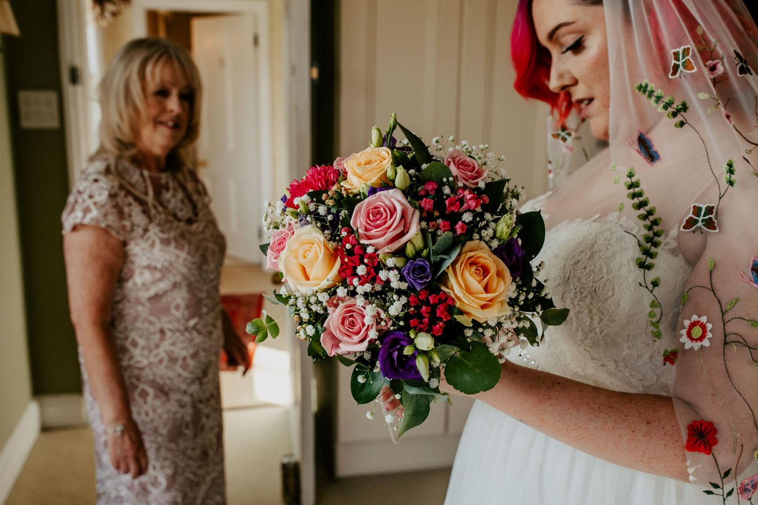 Brides vibrant pink purple and yellow bouquet to matcher her veil and hair