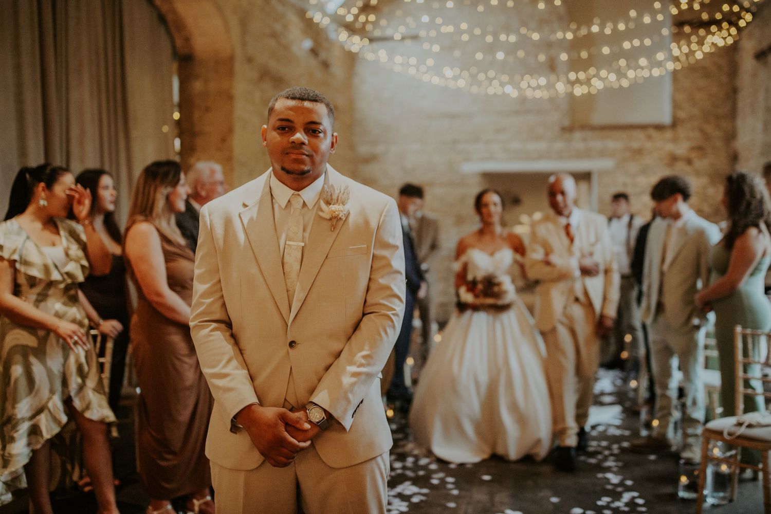 Groom waiting for his bride to walk down the aisle at their wedding ceremony - Lapstone Barn – Chipping Campden, The Cotswolds