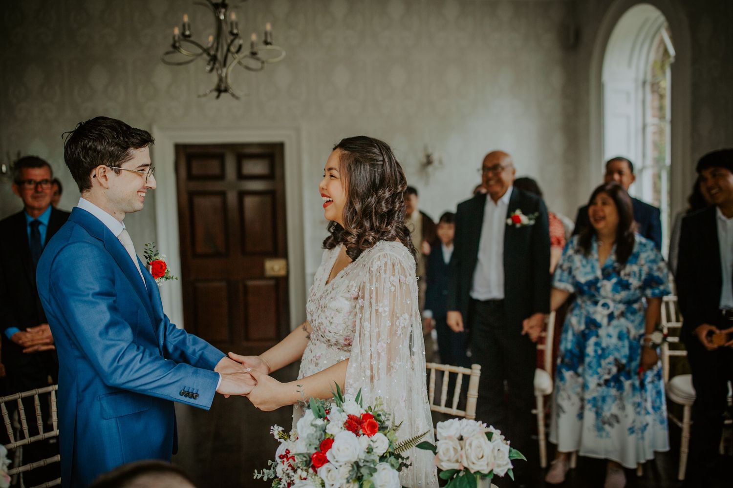 Bride and groom hold hands and smile as they stand together during their wedding ceremony at Morden Park.