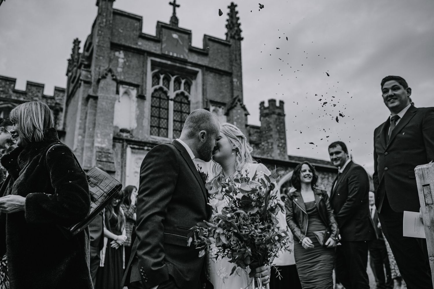 Bride having a confetti kiss outside Braughing Church Hertfordshire, Photographer RELM Photography