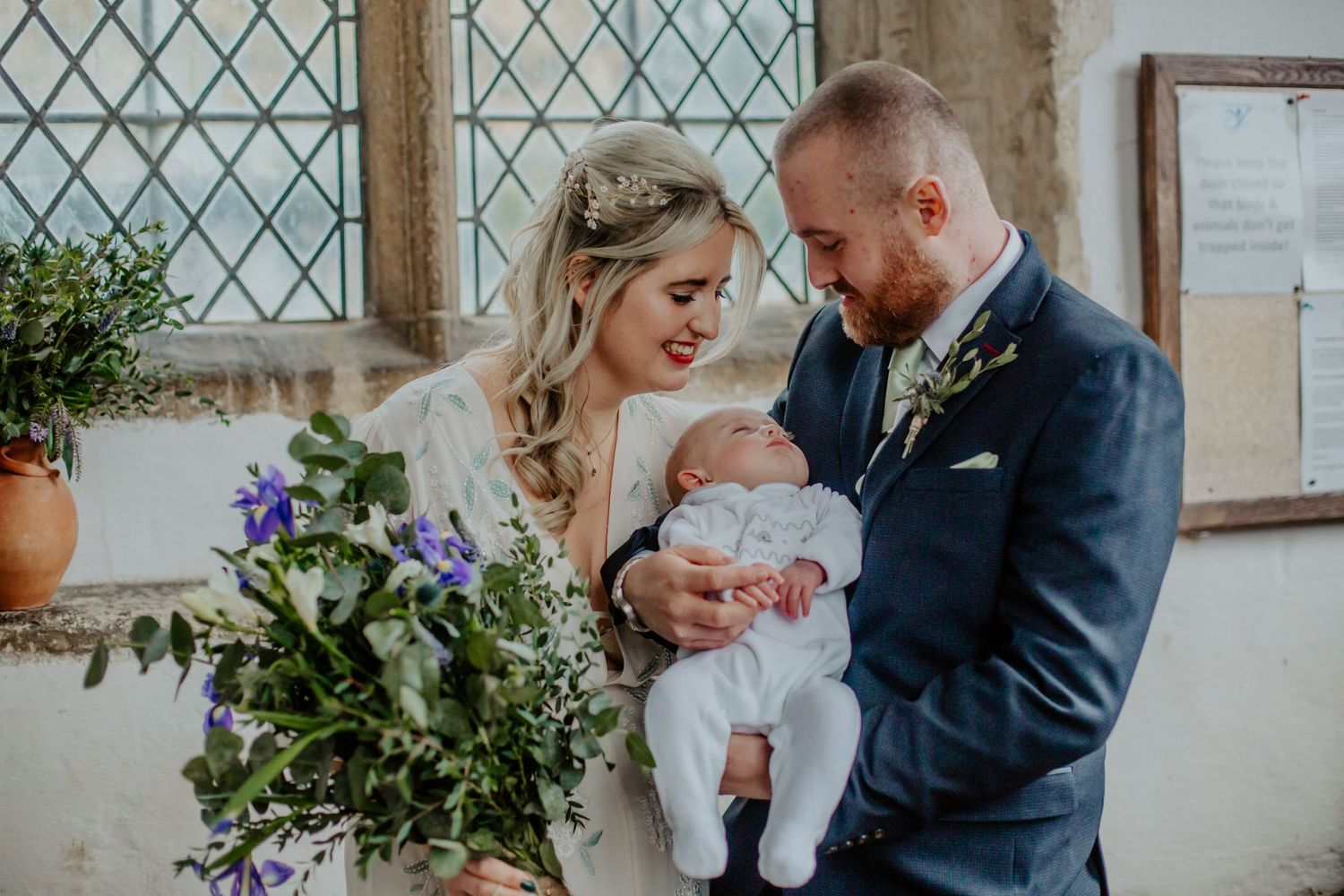 Bride and groom posing with their newborn son at Braughing Church Hertfordshire, Photographer RELM Photography