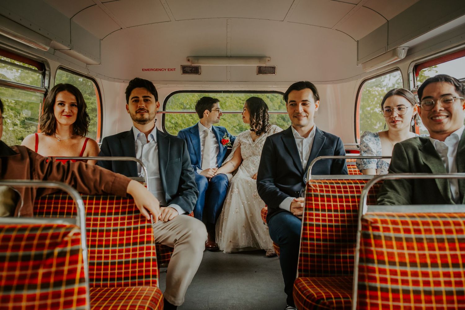 Bride and groom looking lovingly at each other at the back of a London wedding bus.