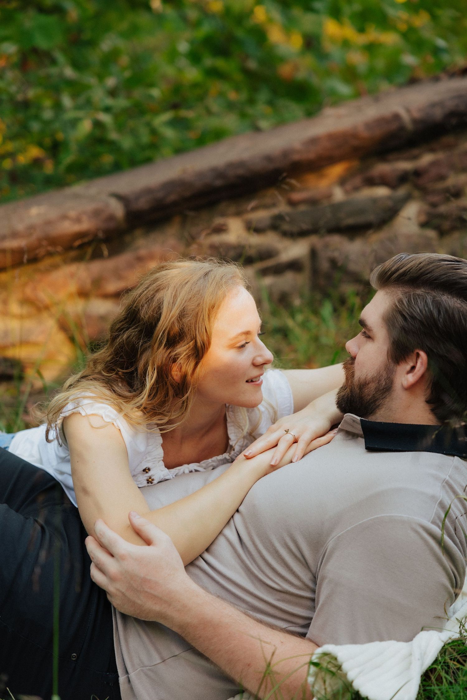 Romantic couple lying on grass, smiling and gazing at each other during golden hour.