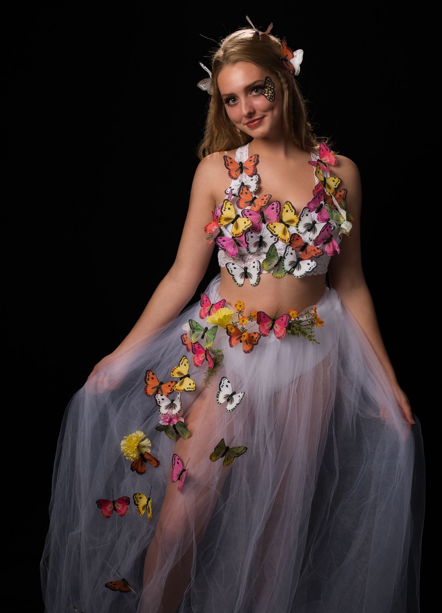 Young woman in a creative butterfly costume with colorful butterflies on white tulle skirt.