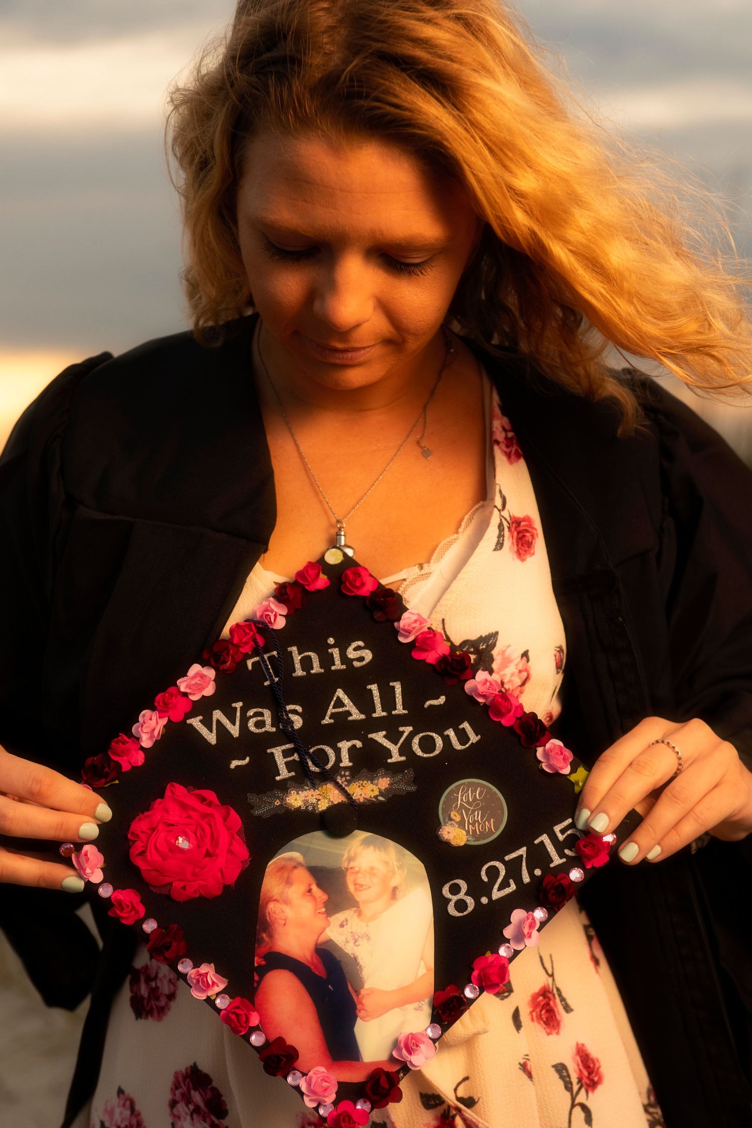 Female graduate holding decorated mortarboard cap reading This Was All For You dated 8.27.15.